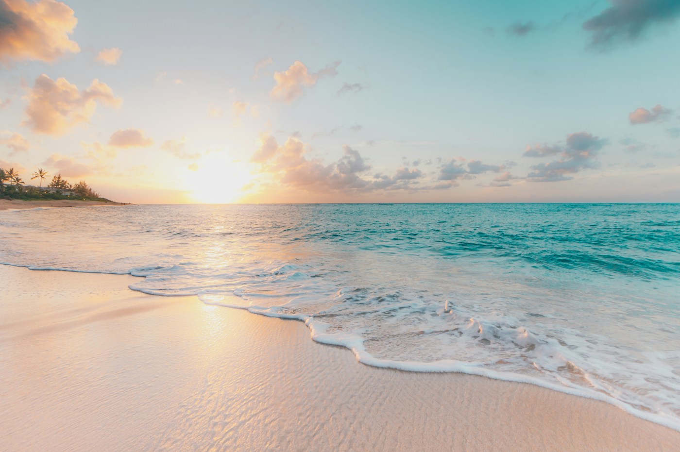 Turquoise ocean rolling onto a sunlit tropical beach
